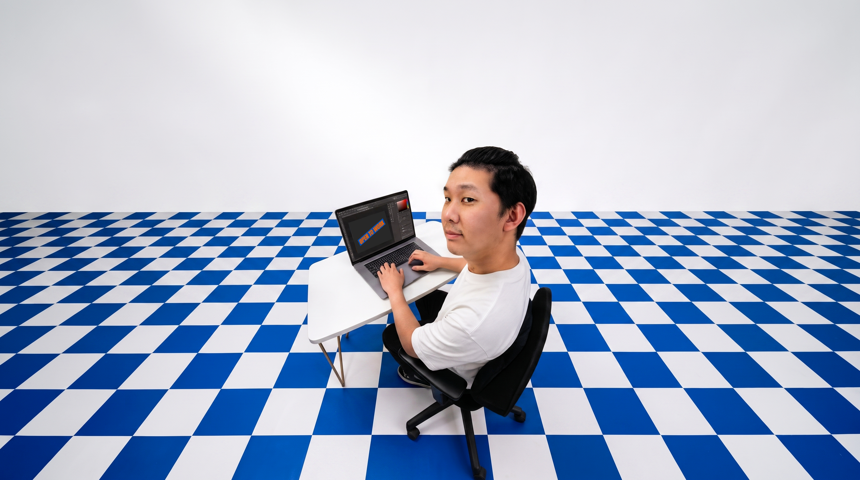 Arms working on a laptop in a blue checker studio